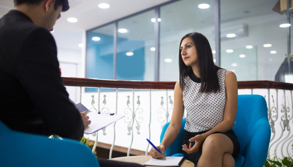 Portrait of confident young woman having meeting with partner. Businessman reading document in lobby, his secretary writing after him. Meeting and partnership concept